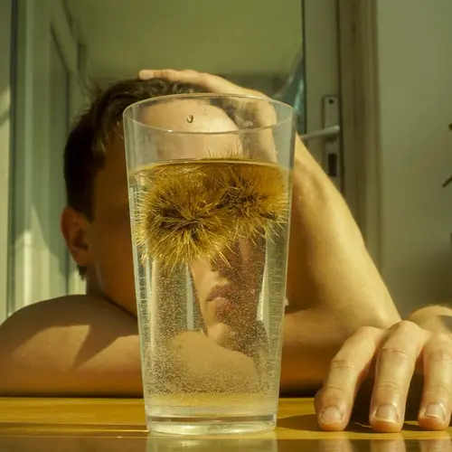 A photograph of a glass on the table with face behind it.