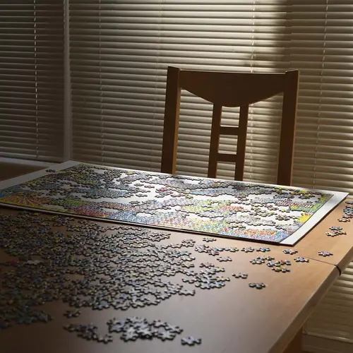A puzzle laid out on a table with a chair behind.