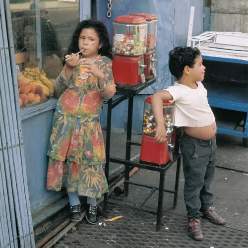Two kids recline on the sweet machines outside a convenience store