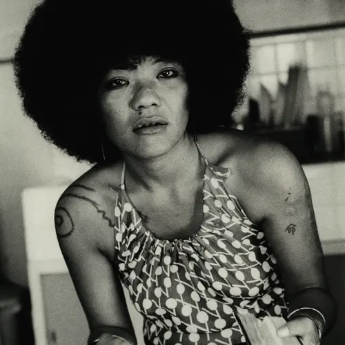 Black and white woman with an afro wearing a printed sleeveless shirt