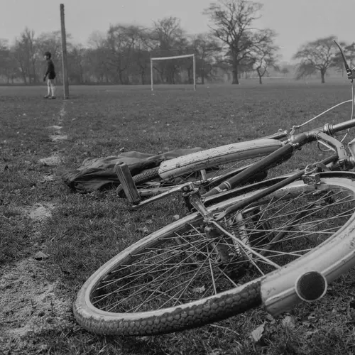 Black and white photograph of a bike on a grass field.