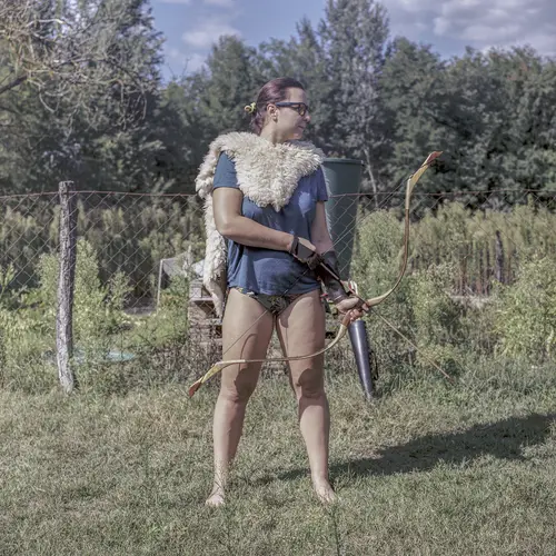 A colour image of a person dressed in a Cupid inspired costume wearing a pair of white feathered wings and holding a bow with an arrow docked in it.