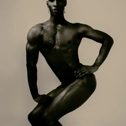A black man poses, body squatting and contorted, with sepia colours 
