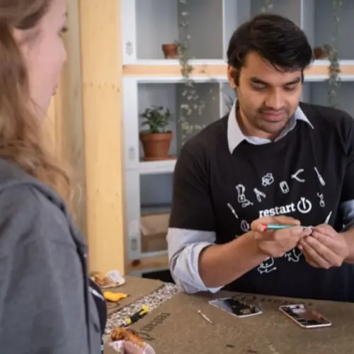 A man from the Restart Project taking a part a smartphone