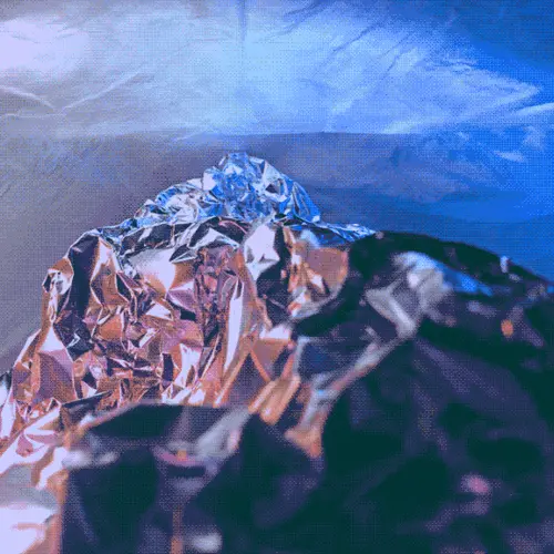 A close up photograph of blue tinted aluminium foil shaped to resemble the peak of a mountain