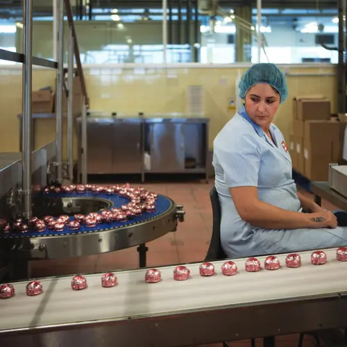 Colour photograph of a woman in a factory next to the Tunnocks production line