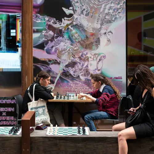 How To Win at Photography exhibition Late with revellers playing chess outside the gallery.