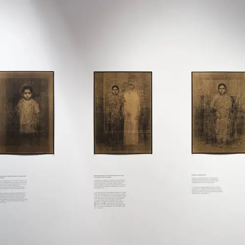 Three gold prints of ghostly people on a white wall