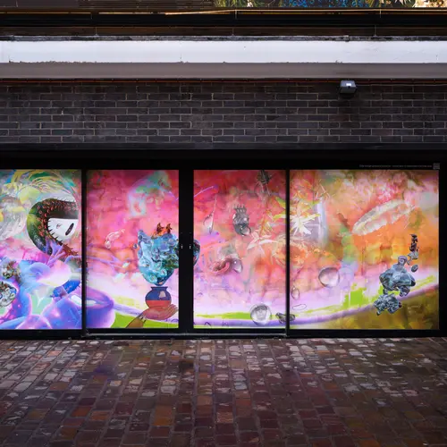 A large vinyl print on a street level window, that shows a vibrant photocollage of 3D objects and archival imahes