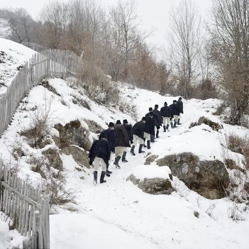 Uniformed men walking in a line in the snow