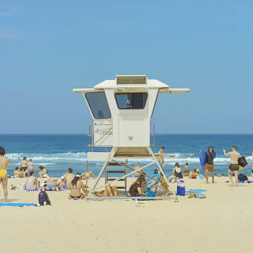 A colour image of a life guard tower on a beach with a bright blue sky across the horizon.