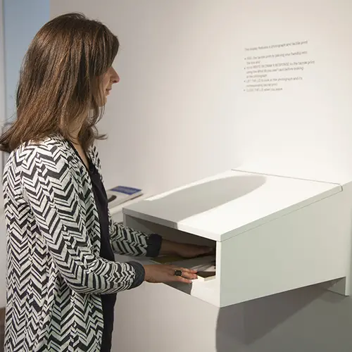 Visitor feeling a tactile print inside an open ended box.