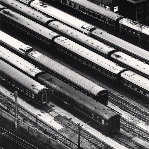 A black and white aerial shot of trains lined up in a trainyard track system. 