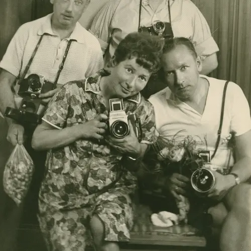 A vintage sepia photograph of Zofia Rydet holding a camera and posing with three men in a friendly huddle.