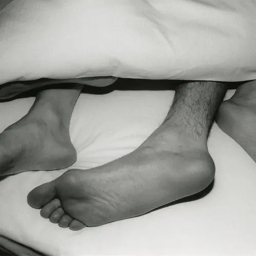 black and white photograph of feet sticking out beneath covers