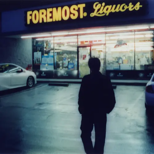 colour photograph of a person walking away from a convenience store