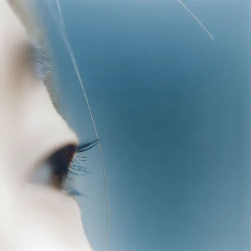 Close-up colour photograph of a person’s eye on a blue background.