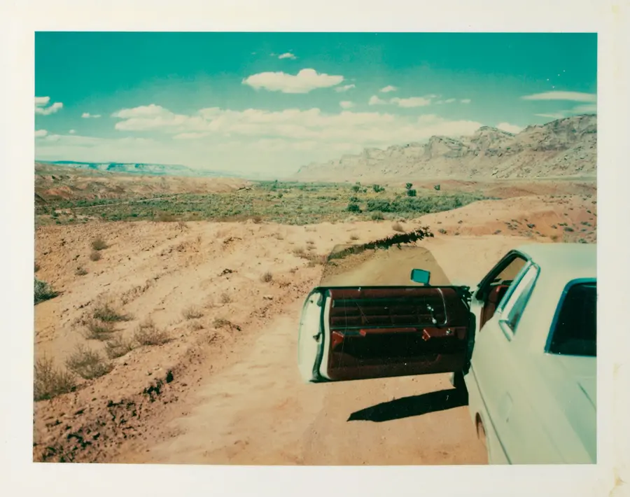 Car parked to the left looking out to a dessert. 