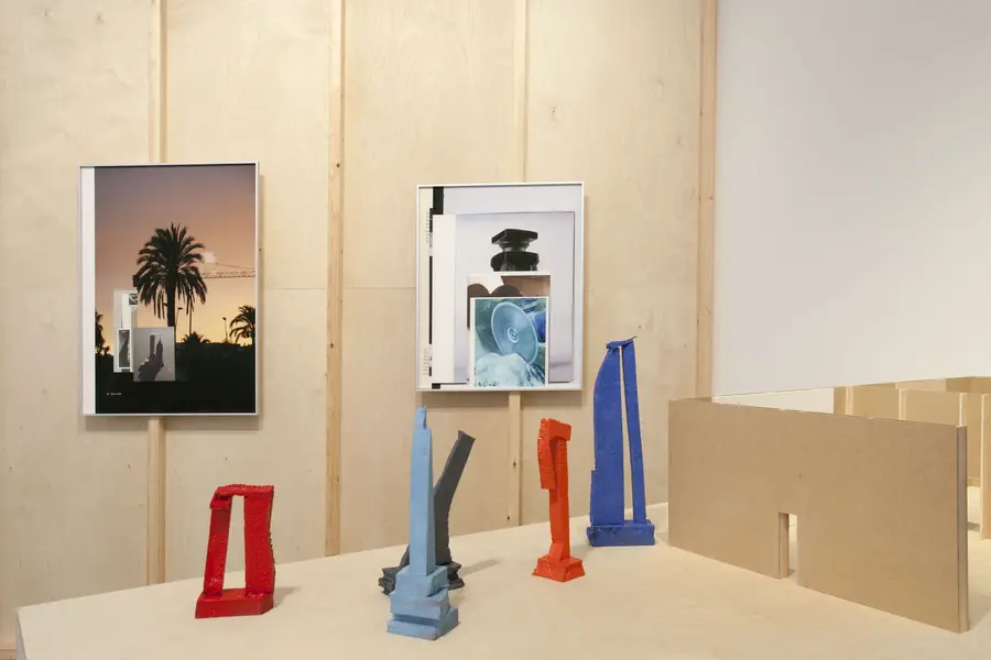 Frames hanging on a wooden wall with sculptures in front.