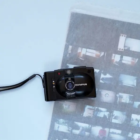 A film camera on top of a contact sheet on a blue background.