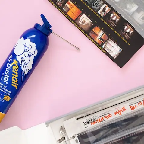 An image of a canister and sleeve with negatives in on a pink background.