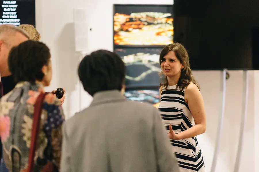 A woman stands talking to a group of people