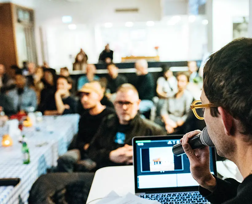 A person holds a microphone and looks out at the audience