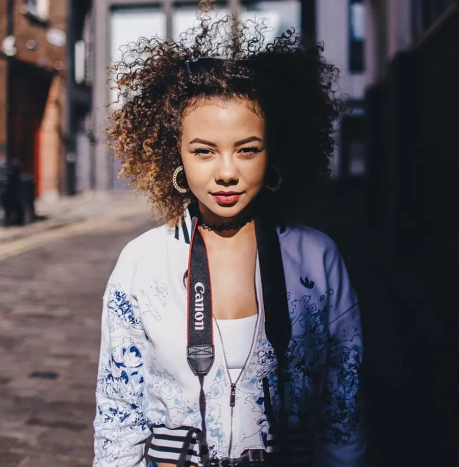 A portrait of a person with a camera around their neck.