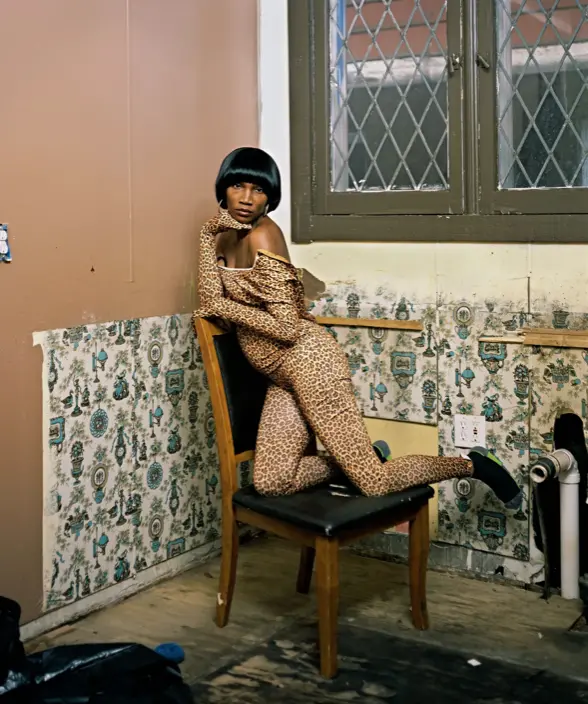 Woman sitting on chair in wallpapered room
