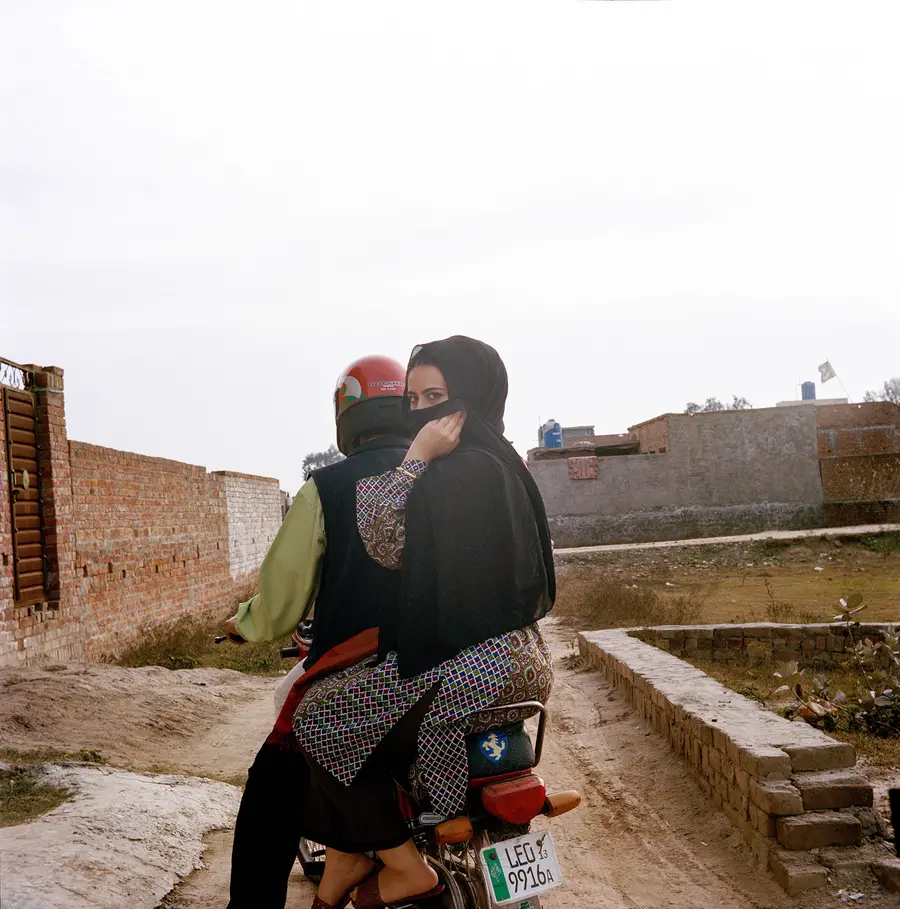 photograph of a man and woman on a motorbike with the woman looking back by Maryam Waheed