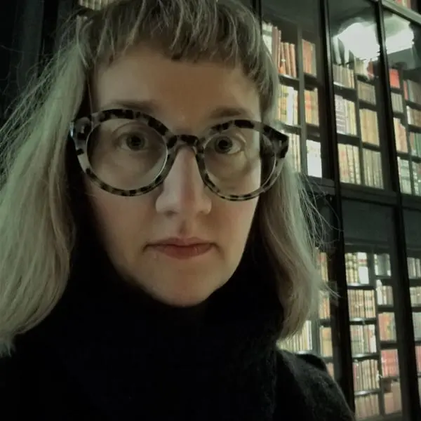 A photo of Elena Marchevska, looking at the camera, wearing glasses