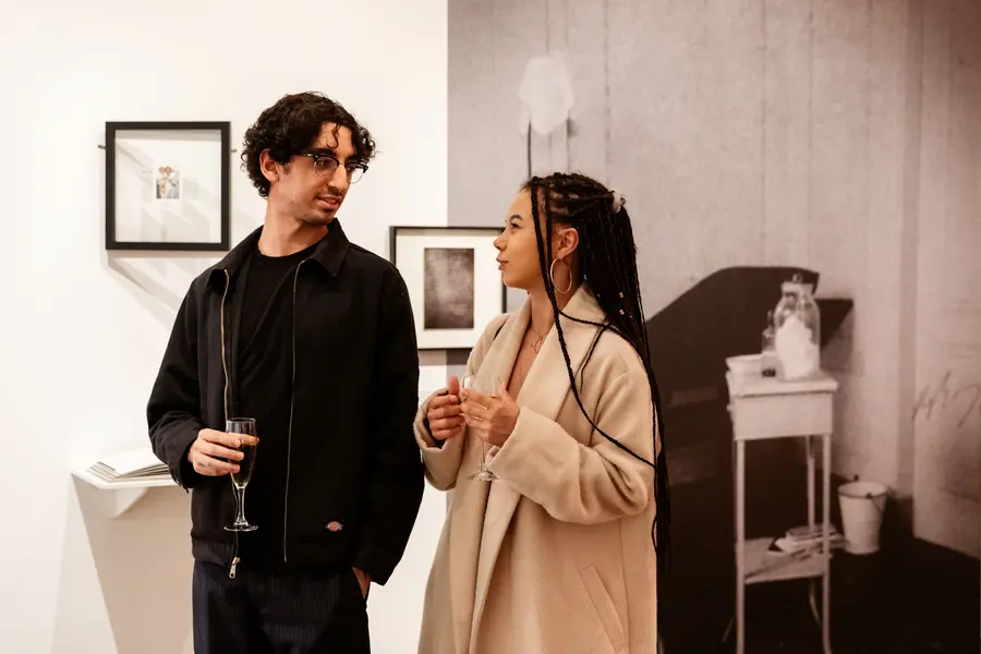Two young people having a glass of champagne and chatting in an exhibition