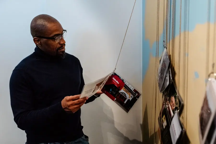 A man looking at a leaflet hanging from the wall in a gallery