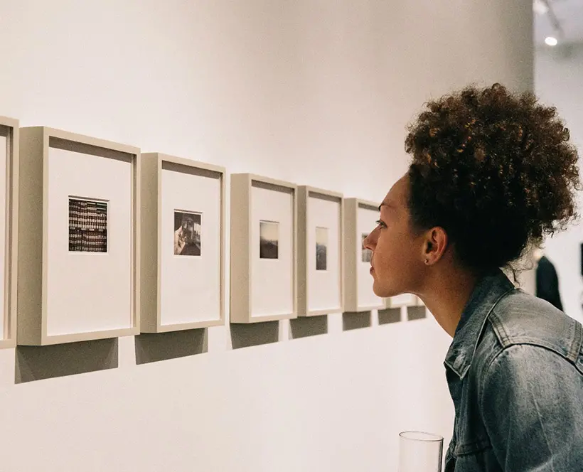 Colour photograph of person looking at framed photographs on the gallery wall