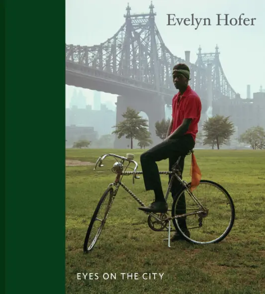 Colour photograph of an Evelyn Hofer book cover titled 'Eyes on the city' with a colour picture of a young man on a bicycle infront of a bridge in New York
