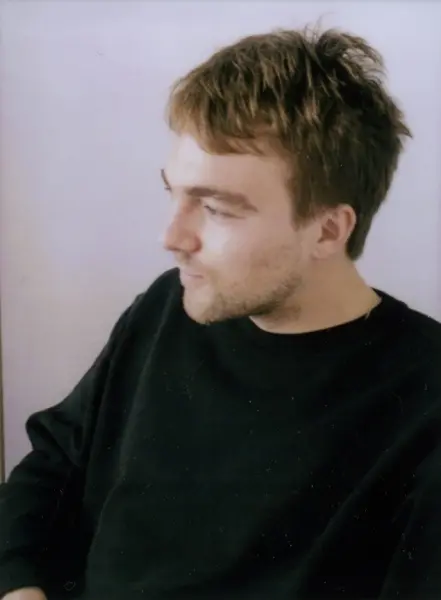 Colour photograph of a man sitting and looking to the left of the camera