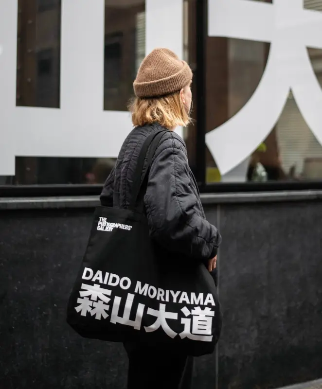 Colour photograph of a person wearing a Daido Moriyama tote bag on their shoulder