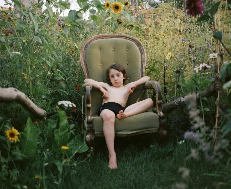 Colour photograph of a young person sitting in a chair in the garden