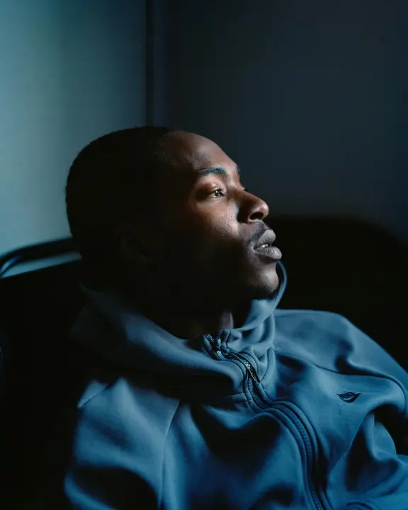 Colour photograph portrait of a person sitting and looking with their head to the right
