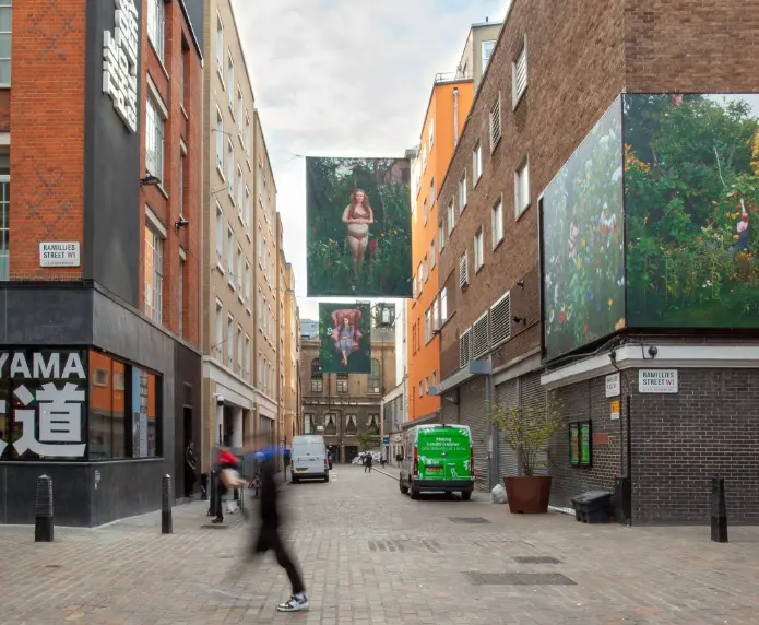 An outdoor exhibition of Sian Davey's work in the Soho Photography quarter, The street outside TPG is line with her photographs of people sat in a garden scene.