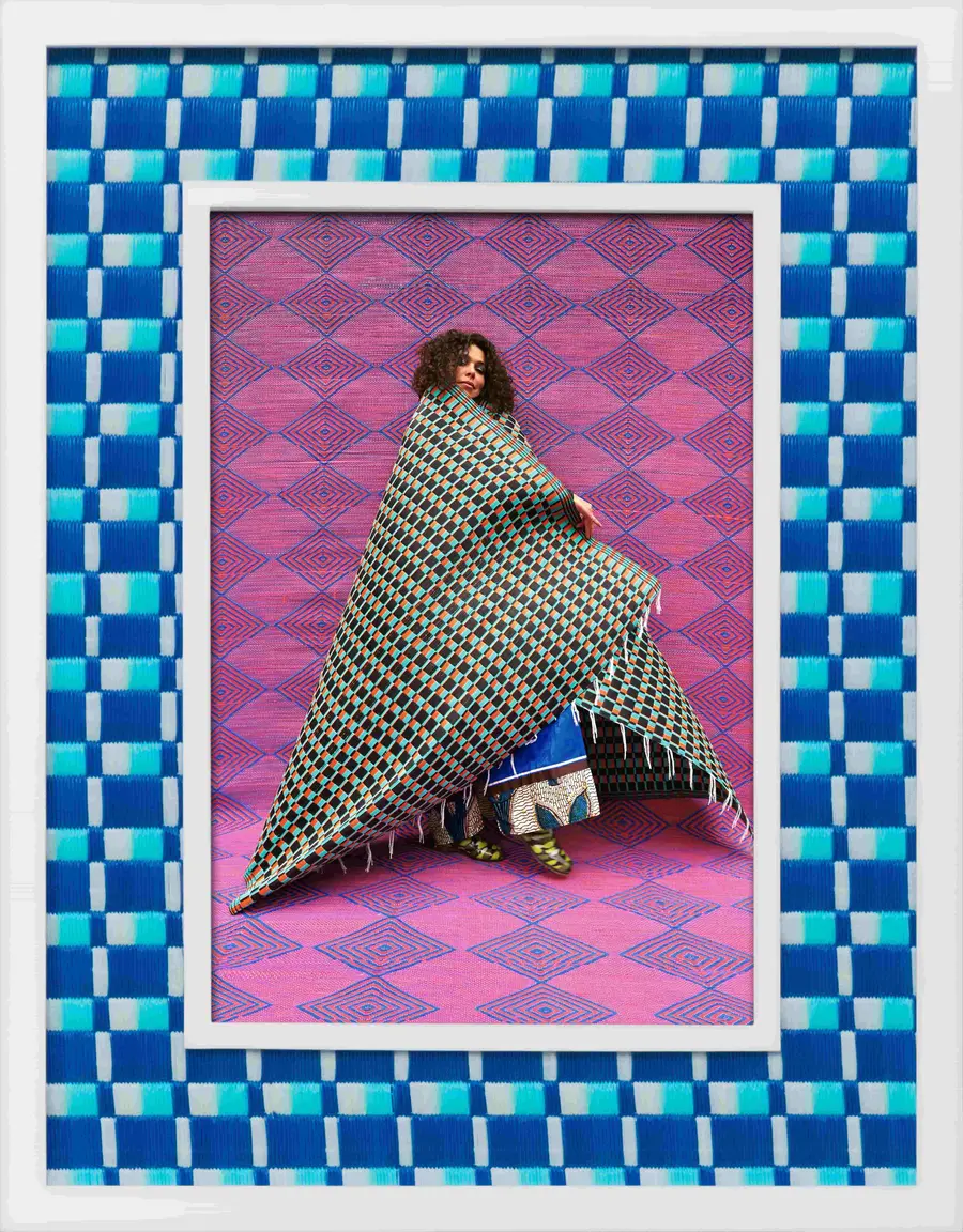 A patterned framed image of a woman draped in a patterned cape.