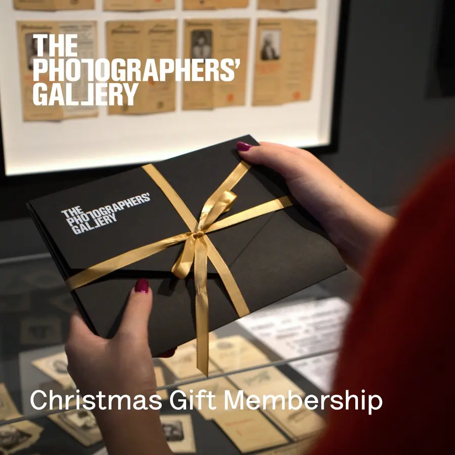 A look over someone's shoulder who is holding a gift membership pack which is a black envelope tied with a golden ribbon.