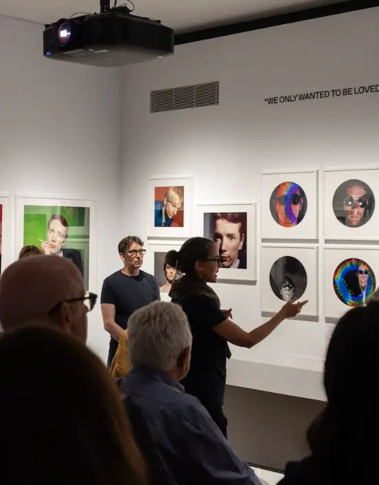 a group of people inside a gallery, being led by a tour leader