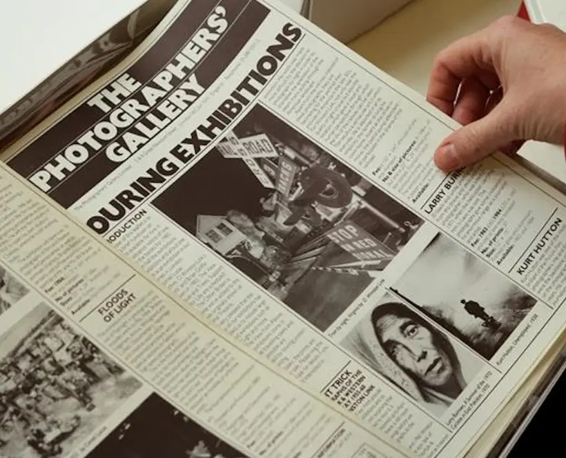 A hand turns a page of a newspaper.