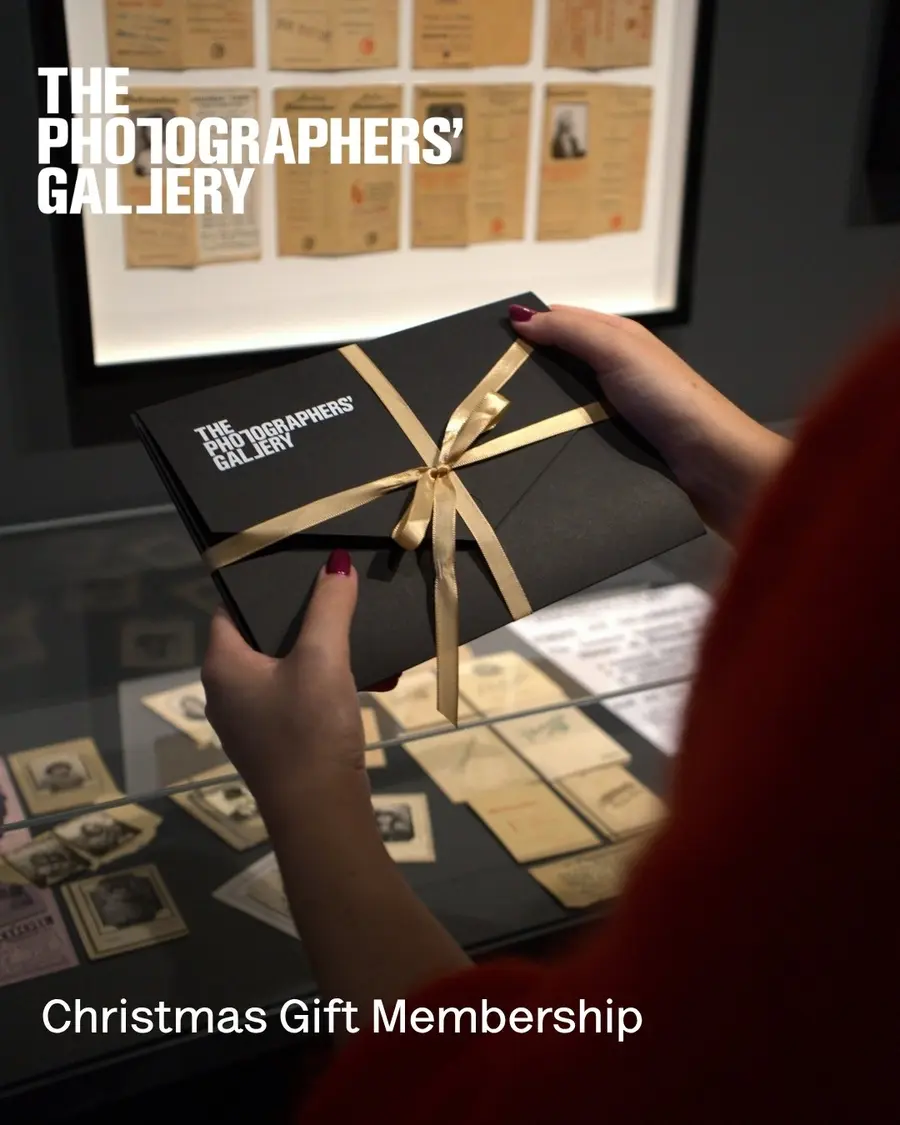 A person holds a black envelope with a gold ribbon wrapped around it.