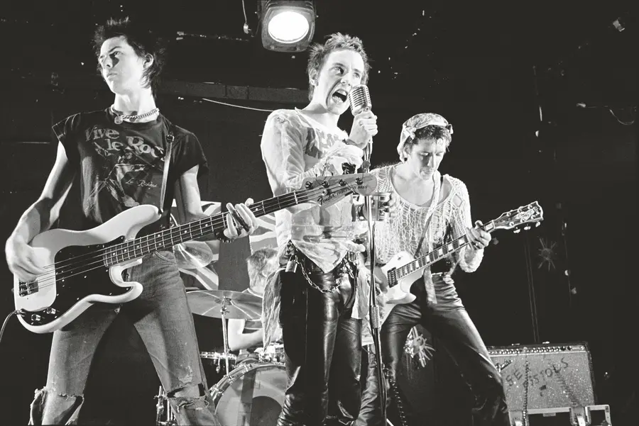 Black and white image of the Sex Pistols singing and playing guitars.
