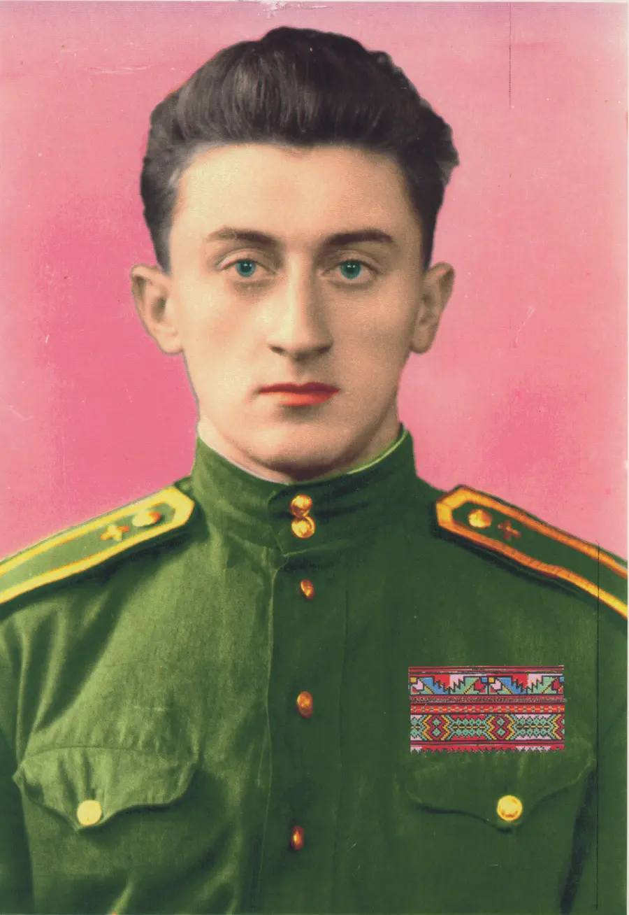 Colour photograph of a young man posed in  green army uniform in front of a pink backdrop