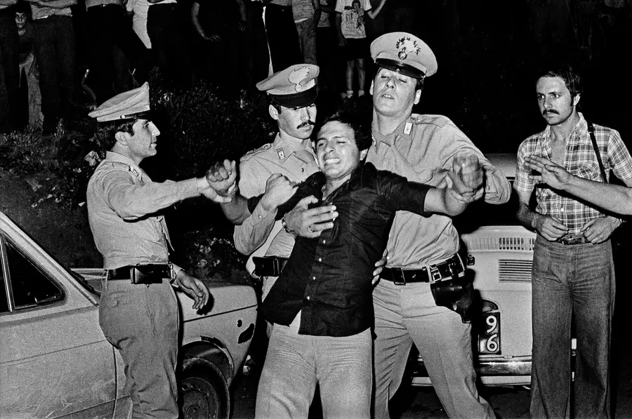 Black and white photograph of a man being dragged away by three police officers, another man stands close by watching the scene.