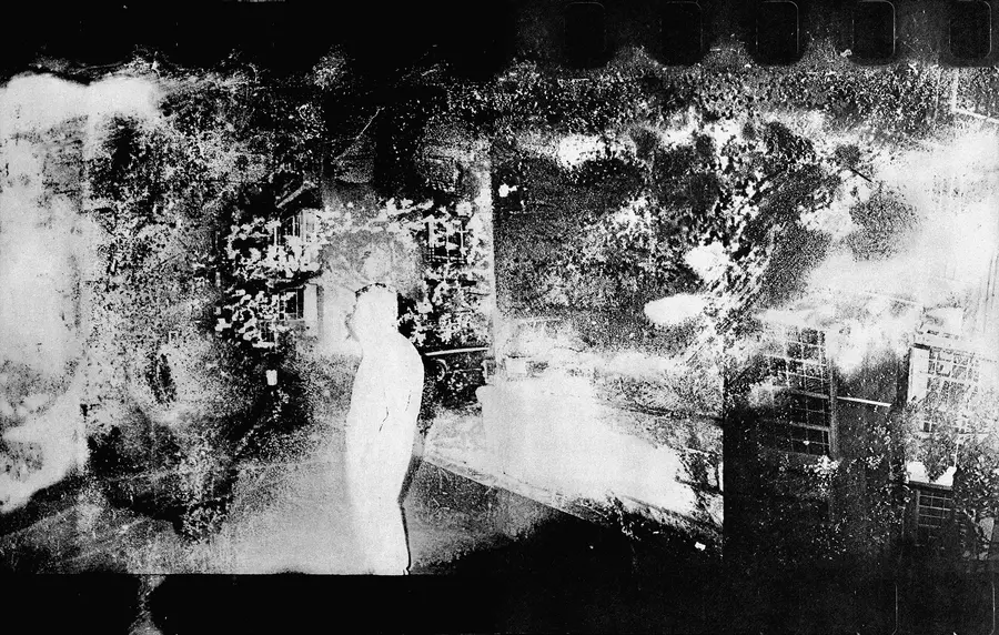 Blurred, grainy and abstract black and white image of a person standing on a street