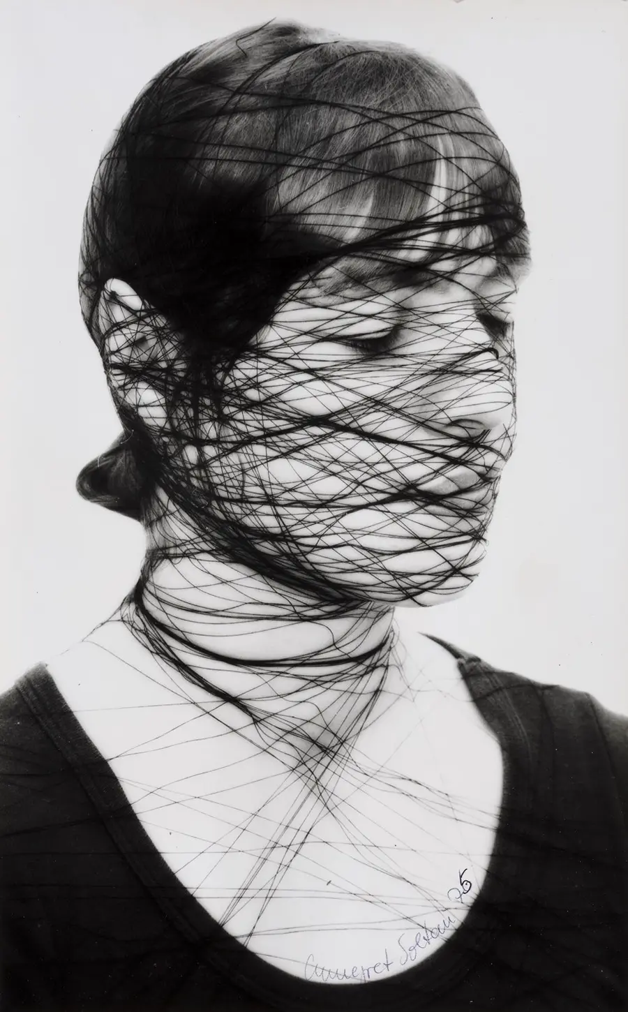 Portrait photograph of a woman with black string wound tightly around her head.